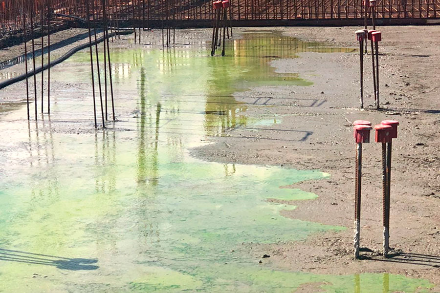Imagem mostra uma laje de concreto com água verde, representando o aditivo para concreto com rastreador